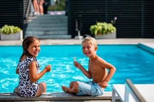 维斯比First Hotel Kokoloko的坐在游泳池旁的男孩和女孩