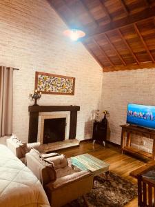 蒙特韦尔迪Chalé Villa Magrini的客厅设有壁炉和电视。