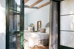 圣巴巴拉Palihouse Santa Barbara的卧室配有白色的床和玻璃门