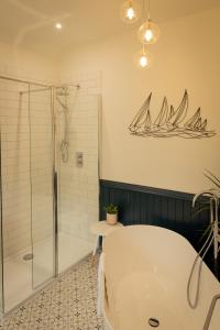 克雷盖拉希Craigellachie Lodge的浴室配有浴缸和淋浴,墙上设有帆船