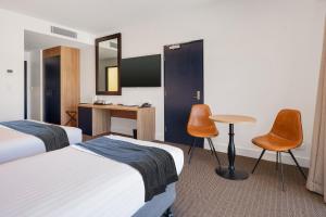 纽卡斯尔Springs Newcastle的酒店客房带两张床和一张桌子以及椅子。