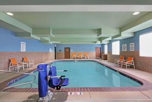 新港纽波特智选假日酒店的医院里的一个游泳池,配有桌椅