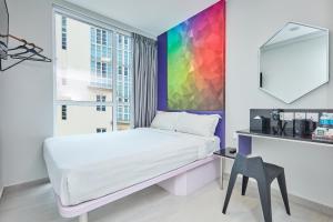 新加坡ibis budget Singapore Ametrine的卧室配有白色的床和色彩缤纷的墙壁