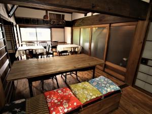 贝冢市ゲストハウス喜平的客房设有木桌、桌子和椅子。