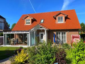 博尔滕哈根Ferienhaus Marina的一座带花园的房屋的橙色屋顶