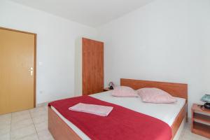 塞尔察Apartments Neva的一间卧室配有一张带红色毯子和两个枕头的床