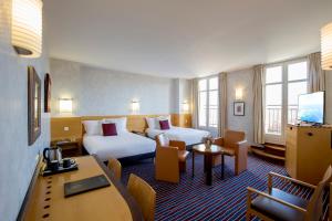 波尔多Hôtel de Normandie的酒店客房设有两张床和一张桌子。