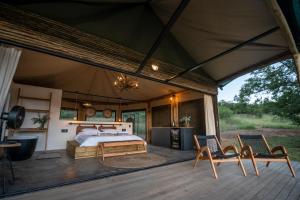 伯格维尔Sasi Africa Luxury Tented Bush Lodge的帐篷内的卧室,甲板上配有一张床