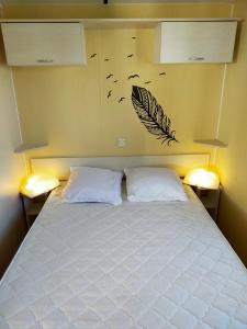 La BétaudièreCamping Cap Soleil île d'Oléron 4 étoiles的卧室配有一张带两个枕头的床,墙上有鸟儿