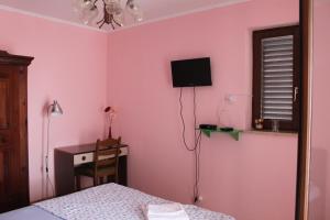 诺瓦利娅Summer house in Novalja的卧室设有粉红色的墙壁、一张床和一张书桌