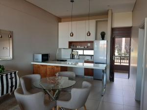 巴利托Zimbali Suite 606的厨房配有桌椅和冰箱。