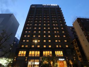 东京Dormy Inn Ikebukuro的一座高大的黑色建筑,有许多窗户