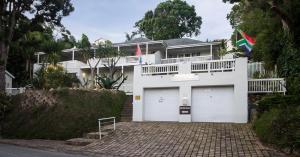 克尼斯纳South Villa Guesthouse&Garden的白色的房子,设有两个车库门和旗帜