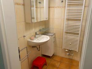 博尔滕哈根2 Zimmer Appartement Poseidon的一间带水槽和红色凳子的小浴室