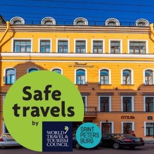 圣彼得堡斯特雅纳亚克伦威尔客旅馆的黄色的建筑,前面有标志