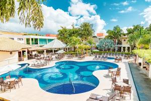 塞古罗港Vitoria Regia Praia Hotel的度假酒店的游泳池配有桌椅