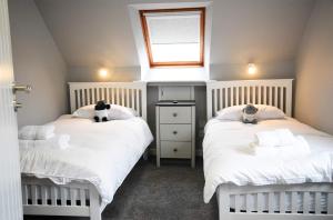 乌伊格5 Glenconon Bed and Breakfast的一间卧室设有两张带白色床单的床和窗户。