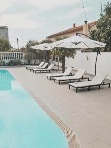 沃迪切俄里翁酒店的游泳池旁的一排躺椅和遮阳伞
