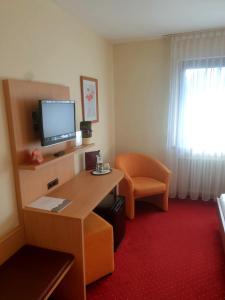 内卡河畔弗赖贝格罗斯勒酒店的酒店客房配有书桌、电视和椅子