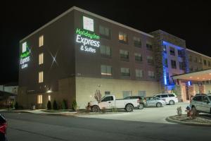 梅里尔维尔Holiday Inn Express & Suites - Merrillville, an IHG Hotel的停车场内停放汽车的酒店大楼