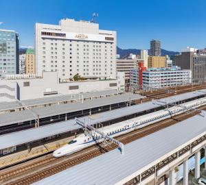 静冈阿索西亚静冈酒店(Hotel Associa Shizuoka)的火车站的轨道上有一辆白色的火车