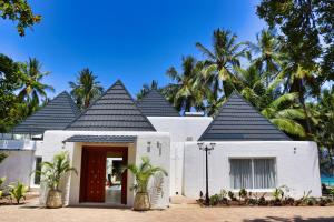迪亚尼海滩Searenity Beach Villa的一座白色的房子,有红色的门和棕榈树