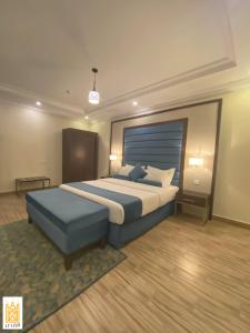 海米斯穆谢特القصر للاجنحة الفندقية الضيافة1的一间卧室配有一张大床和蓝色的搁脚凳