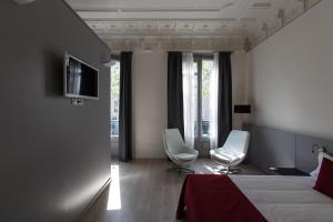 巴塞罗那加泰罗尼亚依扎拉广场住宿加早餐旅馆的酒店客房配有1张床、2把椅子和电视。