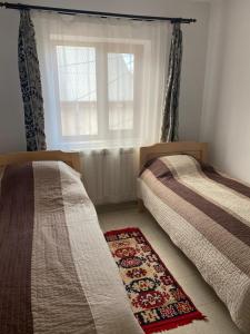 雅西Casa Mărguța的卧室设有两张床,配有窗户和地毯。