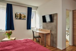 慕尼黑祖尔阿拉哈穆勒酒店的一间卧室配有一张床、一张书桌和一台电视