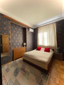 第比利斯Check Inn Tbilisi的一间卧室配有一张带红色枕头的床