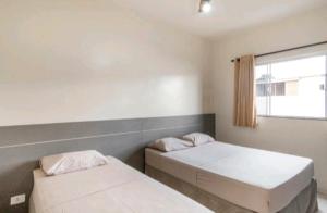 大坎普Nosso Hotel的一间卧室设有两张床和窗户。