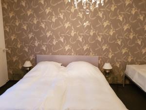 温特贝格Berghotel Natura Bed & Breakfast的一间卧室配有白色床单和花卉壁纸。