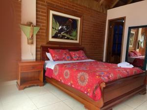 明多Hostal Casa Cultural Mindo的一间卧室配有一张红色棉被的床