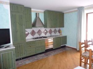 FiavèApartment in Fiavè 24164的一间设有绿色橱柜和一台平面电视的厨房