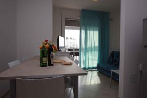 罗索利纳马雷Two-Bedroom Apartment Rosolina Mare near Sea 3的厨房配有带瓶装葡萄酒的桌子