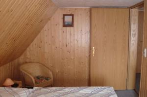 诺因多夫Apartment Neuendorf - Hiddensee 2的卧室设有木墙、一张床和椅子