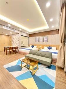 归仁FLC SEA TOWER Quy Nhon- Kizz House的客房设有两张床、一张沙发和一张桌子。