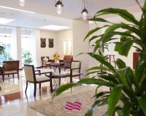 吉达吉达皇冠假日酒店的大堂设有桌椅和盆栽植物