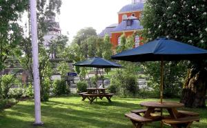 瑟德港Prästgården Hotell & Bryggeri的公园内两张带遮阳伞的野餐桌