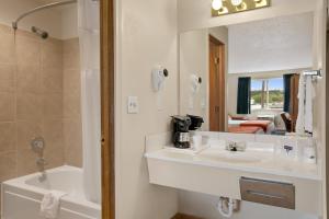 法夫塔科马港旅舍的一间带水槽、浴缸和镜子的浴室