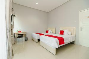 巨港RedDoorz @ Jalan Demang Lebar Raya Palembang的白色卧室内的两张床,配有红色和白色床单