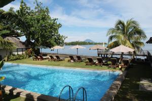 美娜多可可蒂诺斯美娜多酒店的水边带椅子和遮阳伞的游泳池
