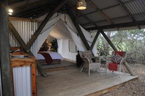 维德尼斯Heritage Glamping, Woodlands tent的木制甲板上的帐篷,配有一张床和椅子