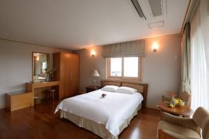 西归浦市守尔迷你酒店的卧室配有一张白色的大床和一张桌子