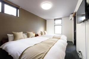 京都JP INN Kyotoeki Kita Gakurincho的带3张大型白色床和窗户的客房