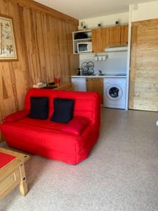 蒙特克拉Grand studio 5 personnes Station Familiale Montclar的厨房里配有带两个枕头的红色沙发