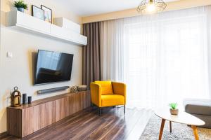 格沃古夫Bulwar Apartament的一间带电视和黄椅的客厅