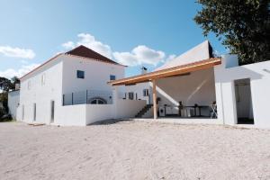 Azoia de BaixoAzoia 10 - Casas de Campo & Hostel的海滩上的白色建筑,毗邻房子