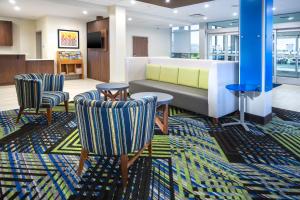 迈尔斯堡Holiday Inn Express & Suites - Fort Myers Airport, an IHG Hotel的大堂配有沙发和两把椅子